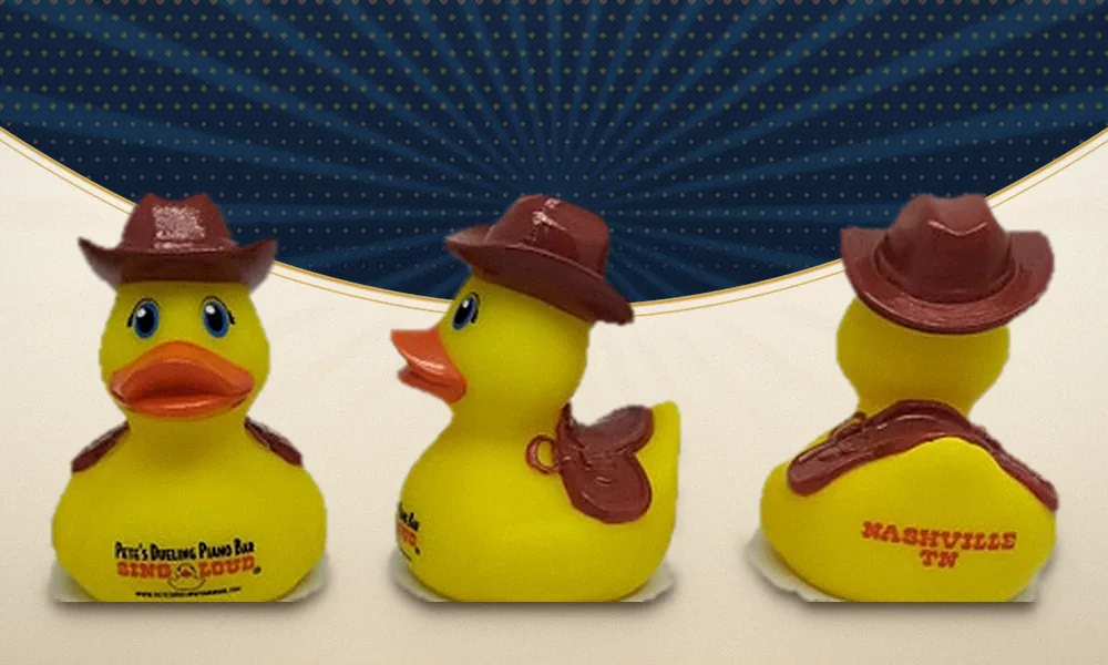 A finished hand-painted custom duck shown from the front, side and back, with a sculpted cowboy hat and saddlebag pulled from a dedicated mold